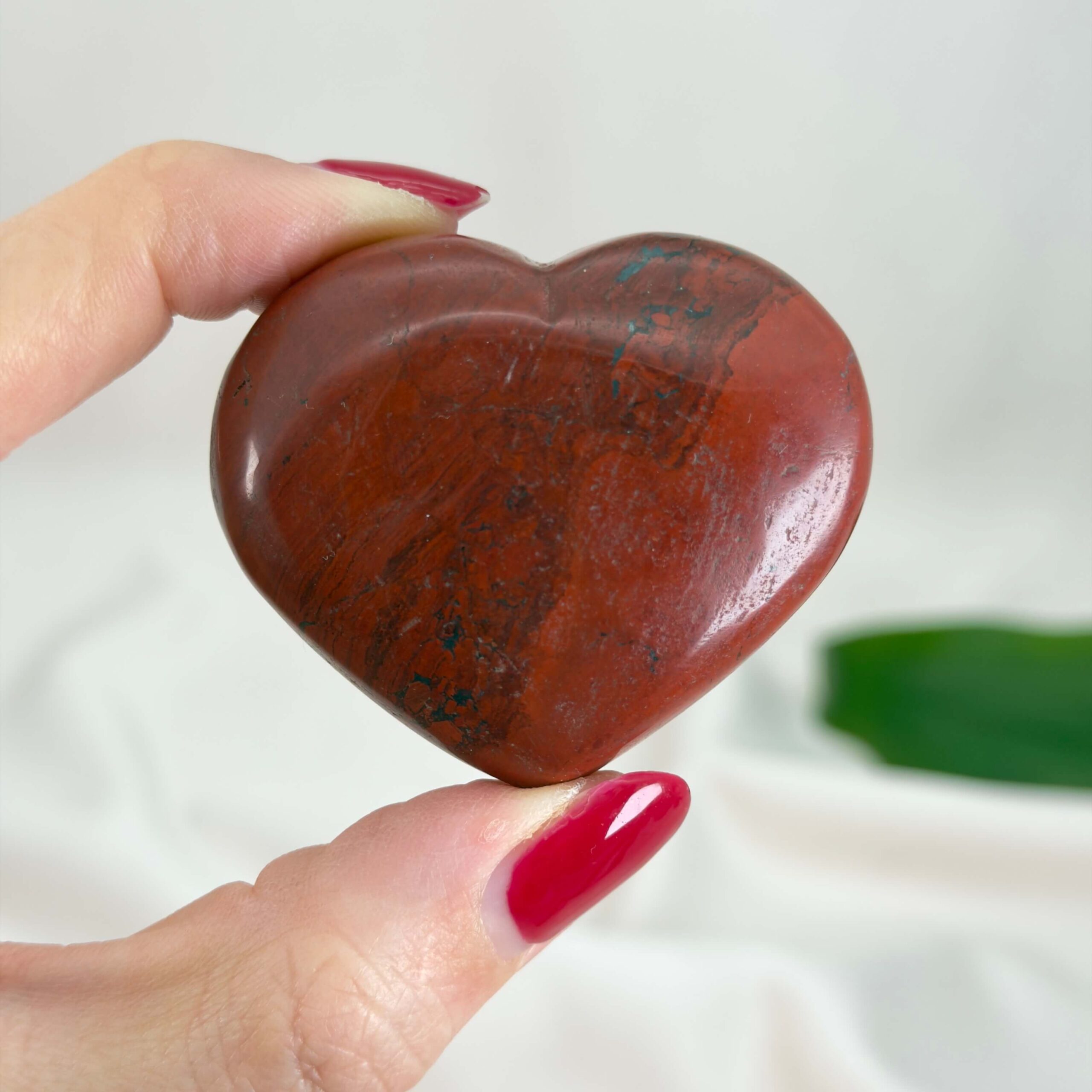 Rød Jaspis Hjerte krystal sten i hånd på hvid baggrund