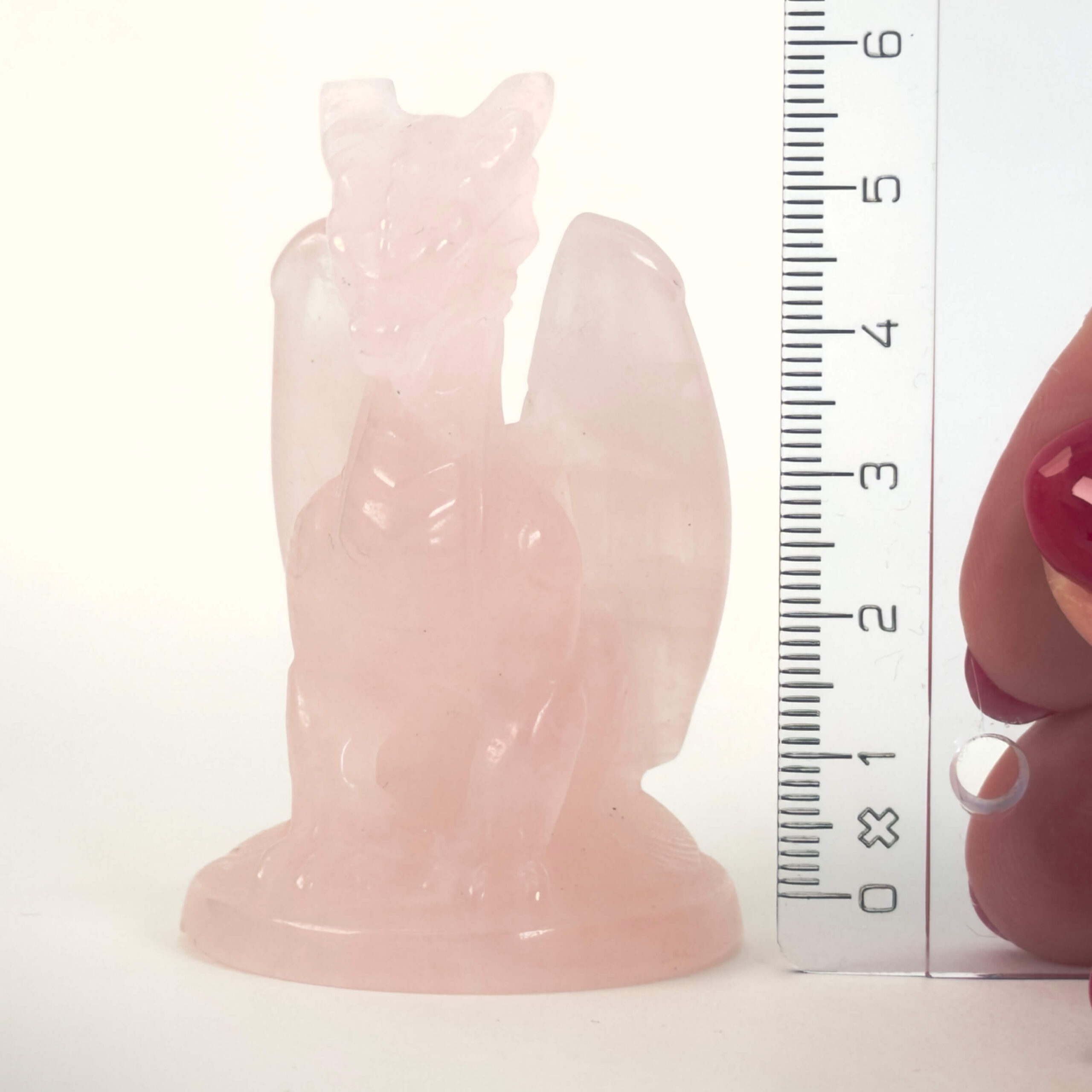 Rosakvarts Drage krystal sten med lineal på hvid baggrund