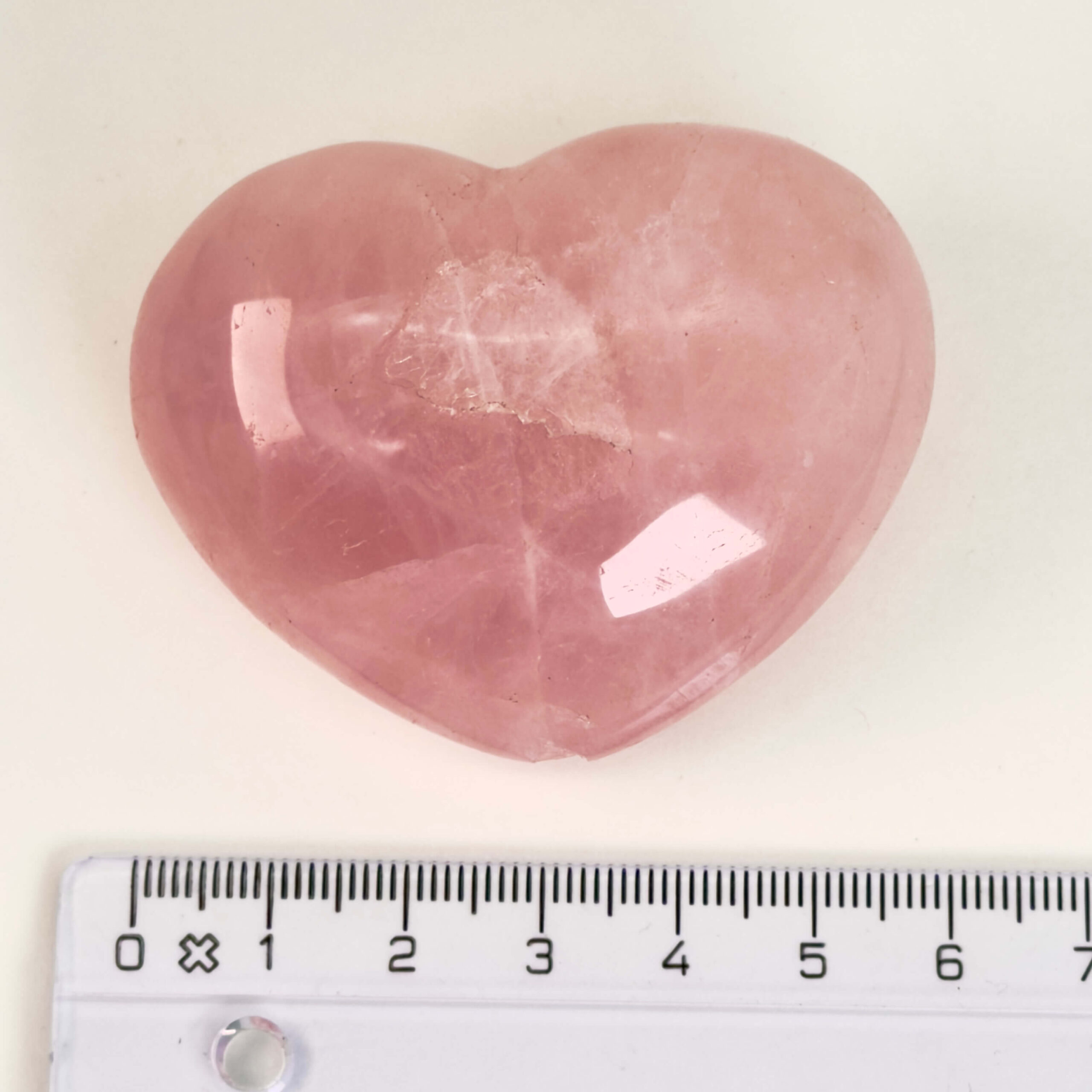 Rosakvarts Hjerte Krystal Sten på hvid baggrund med lineal