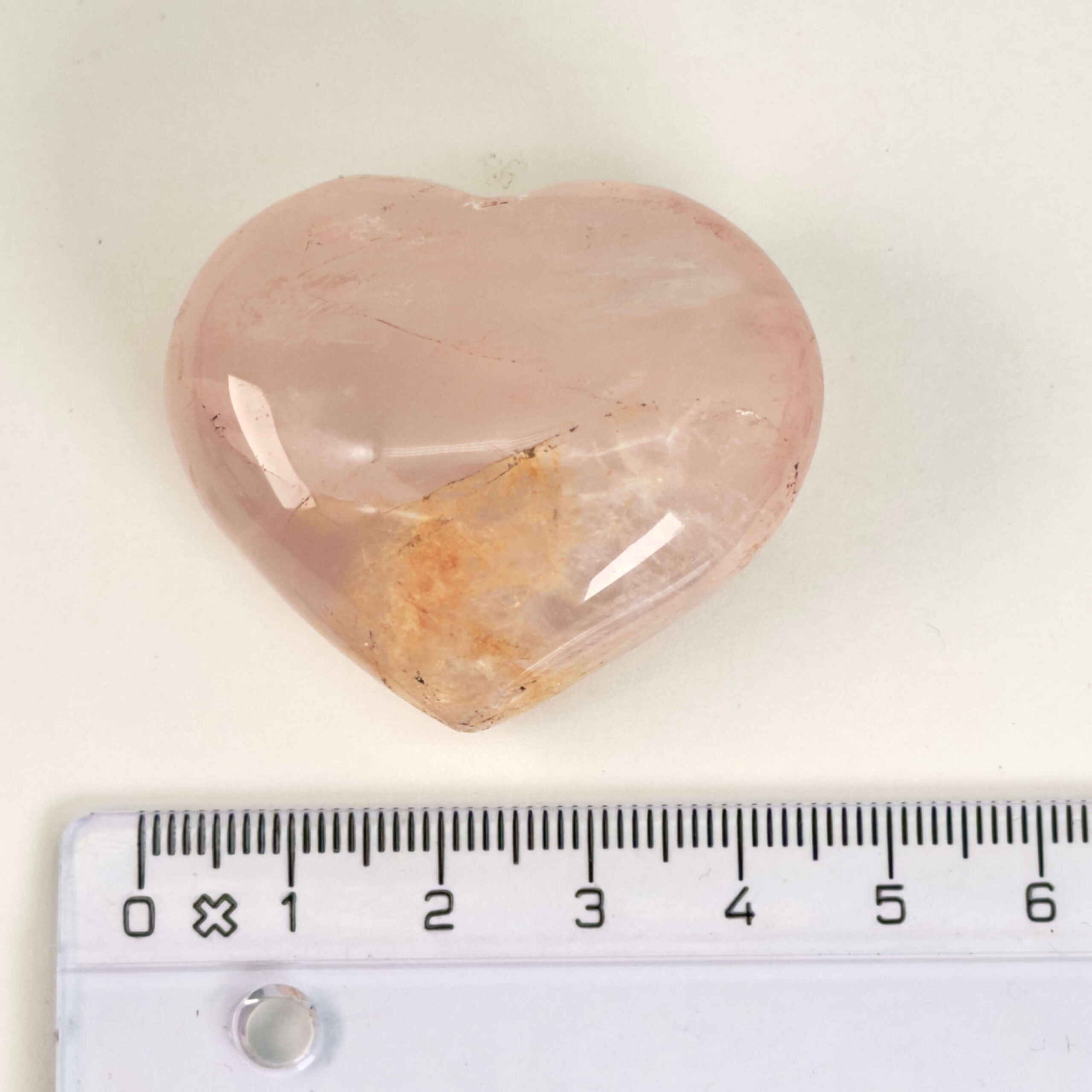 Rosakvarts Hjerte Krystal Sten på hvid baggrund med lineal