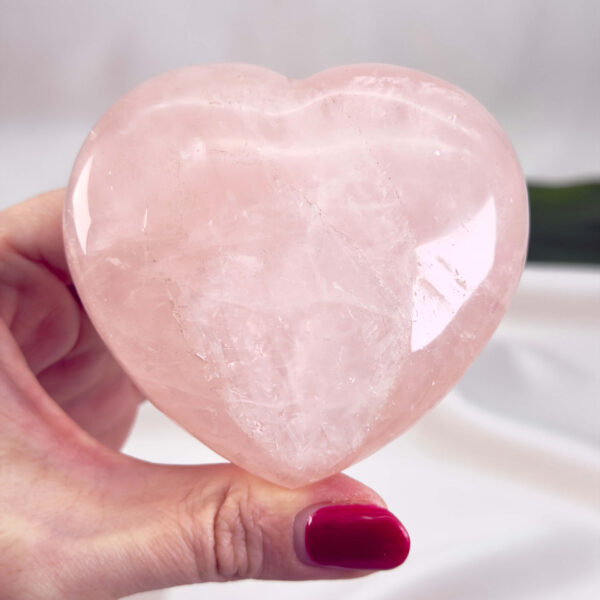 Rosakvarts Hjerte Krystal Sten på hvid baggrund i hånd