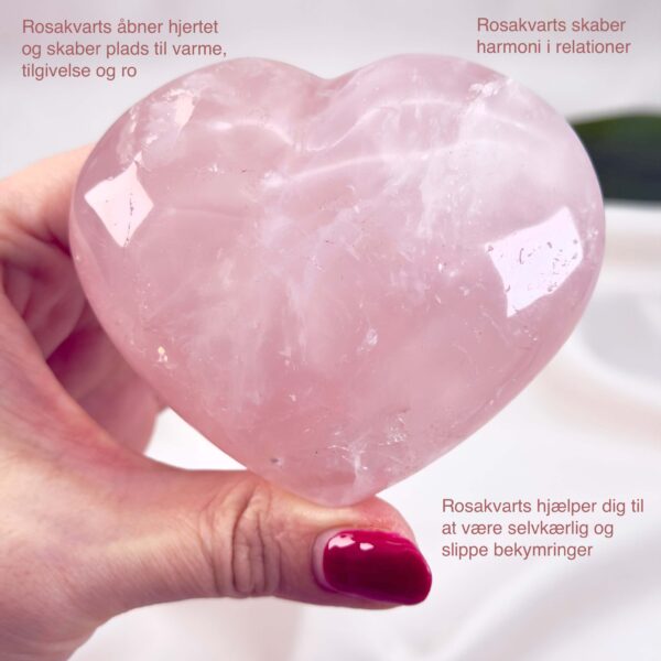 Rosakvarts Hjerte Krystal Sten på hvid baggrund i hånd med tags