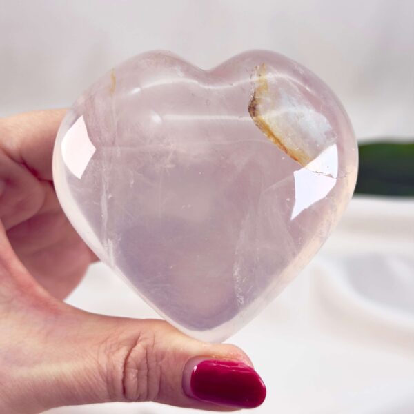 Rosakvarts Hjerte Krystal Sten på hvid baggrund i hånd