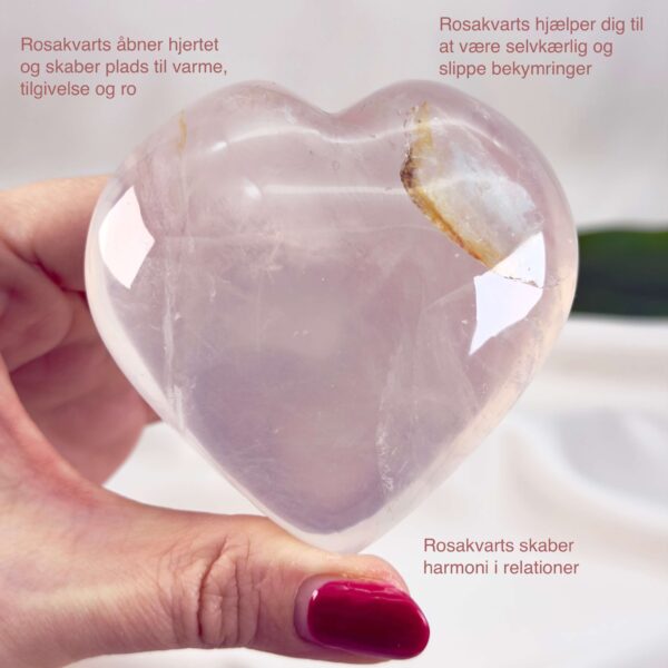 Rosakvarts Hjerte Krystal Sten på hvid baggrund i hånd med tags
