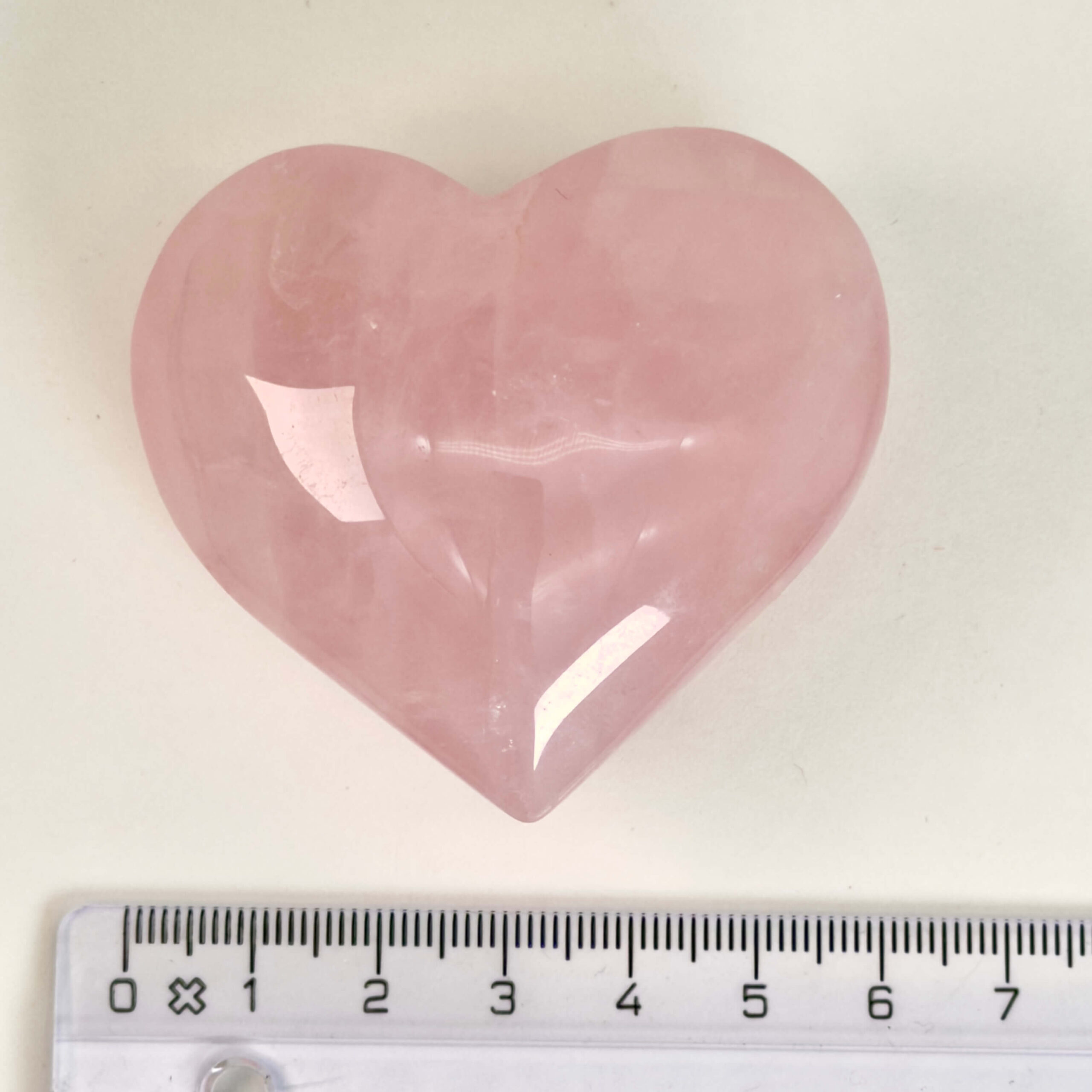 Rosakvarts Hjerte Krystal Sten på hvid baggrund med lineal