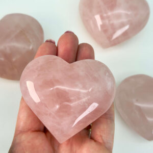 Rosakvarts Hjerte Krystal Sten på hvid baggrund i hånd