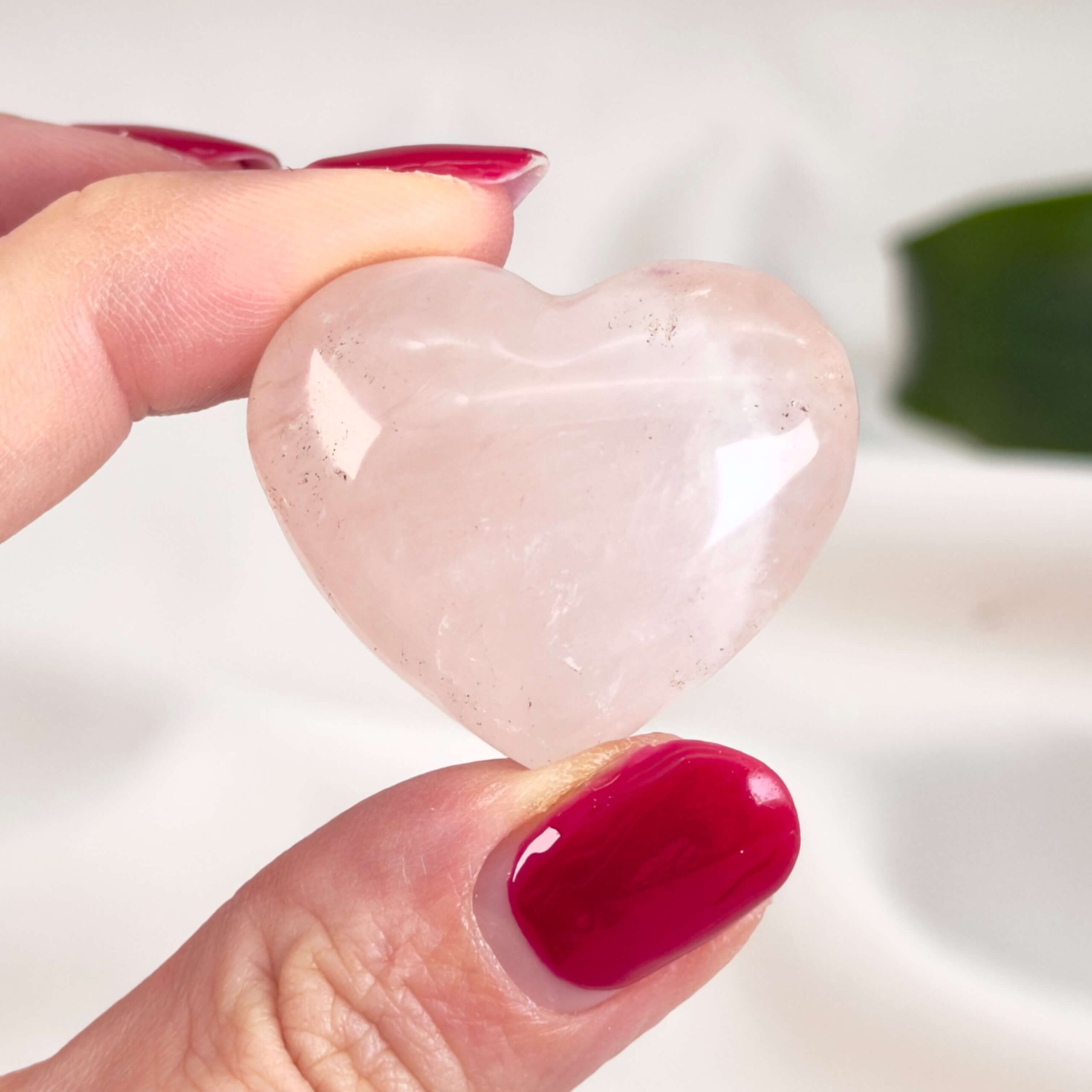Rosakvarts Hjerte Krystal Sten på hvid baggrund i hånd