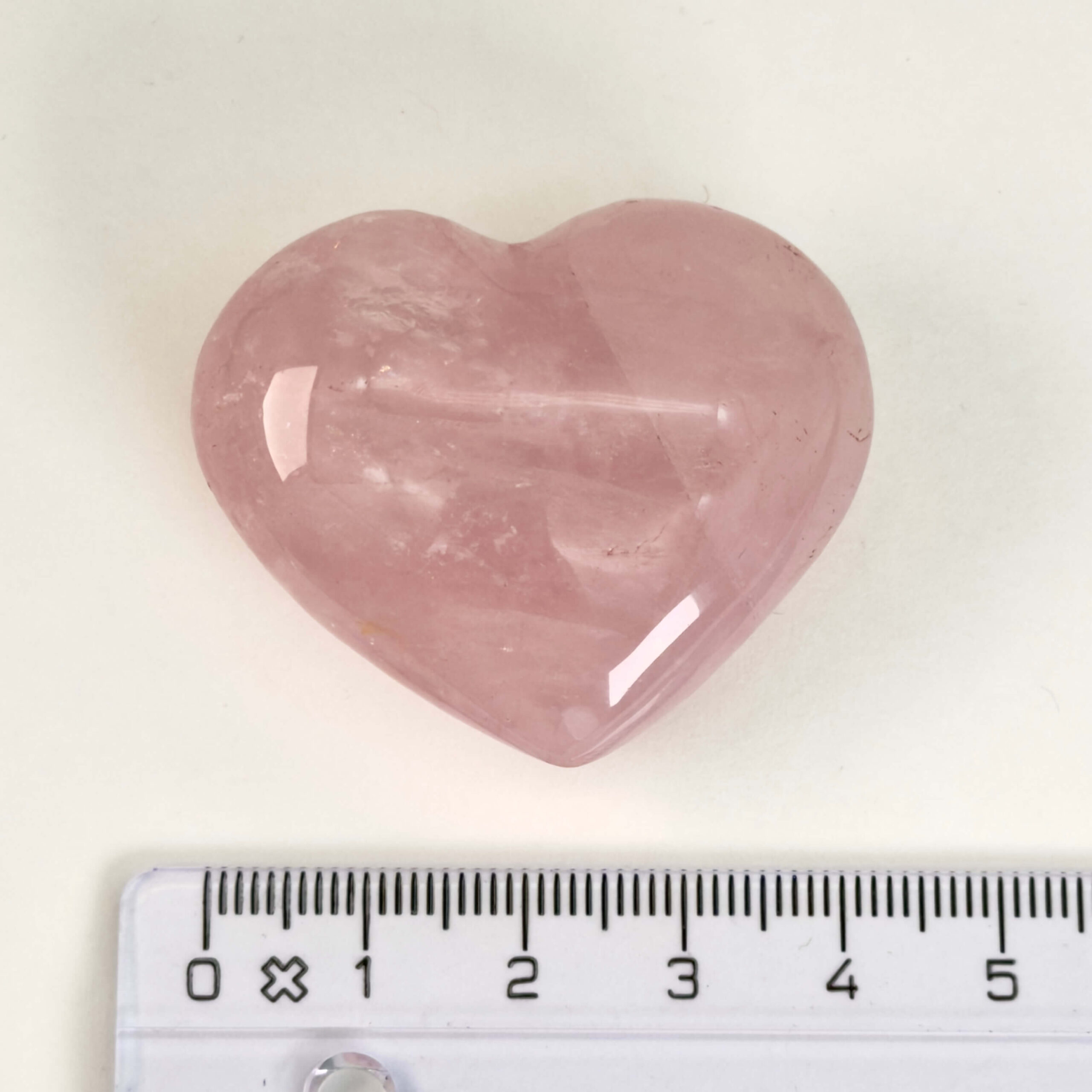 Rosakvarts Hjerte Krystal Sten på hvid baggrund med lineal