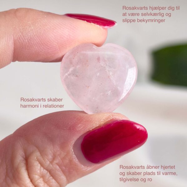 Rosakvarts Hjerte Krystal Sten på hvid baggrund i hånd med tags