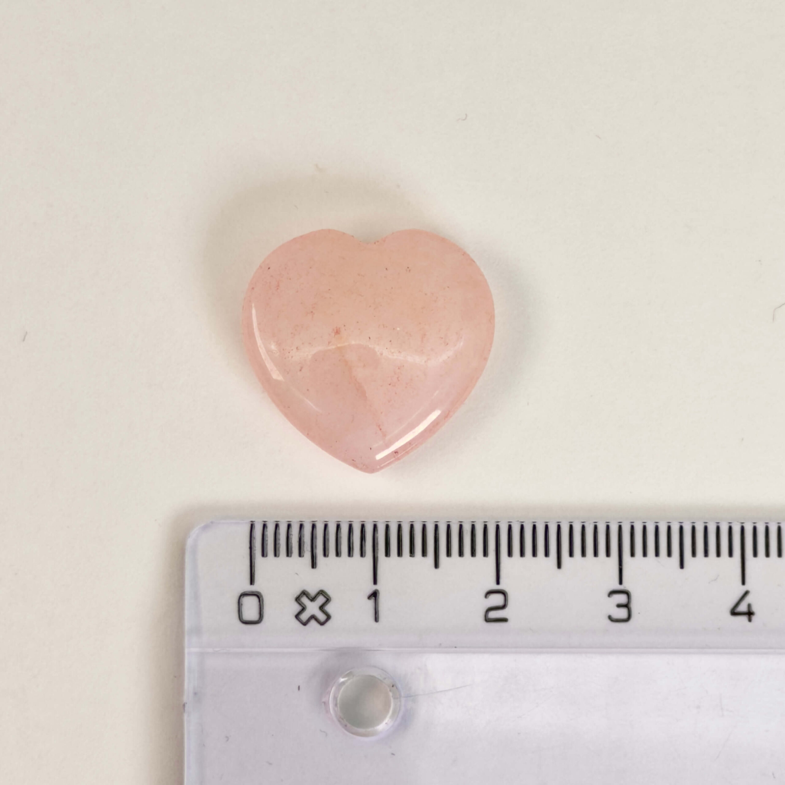 Rosakvarts Hjerte Krystal Sten på hvid baggrund med lineal