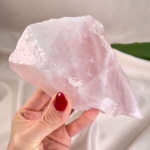 Rosakvarts Rå krystal sten i hånd på hvid baggrund