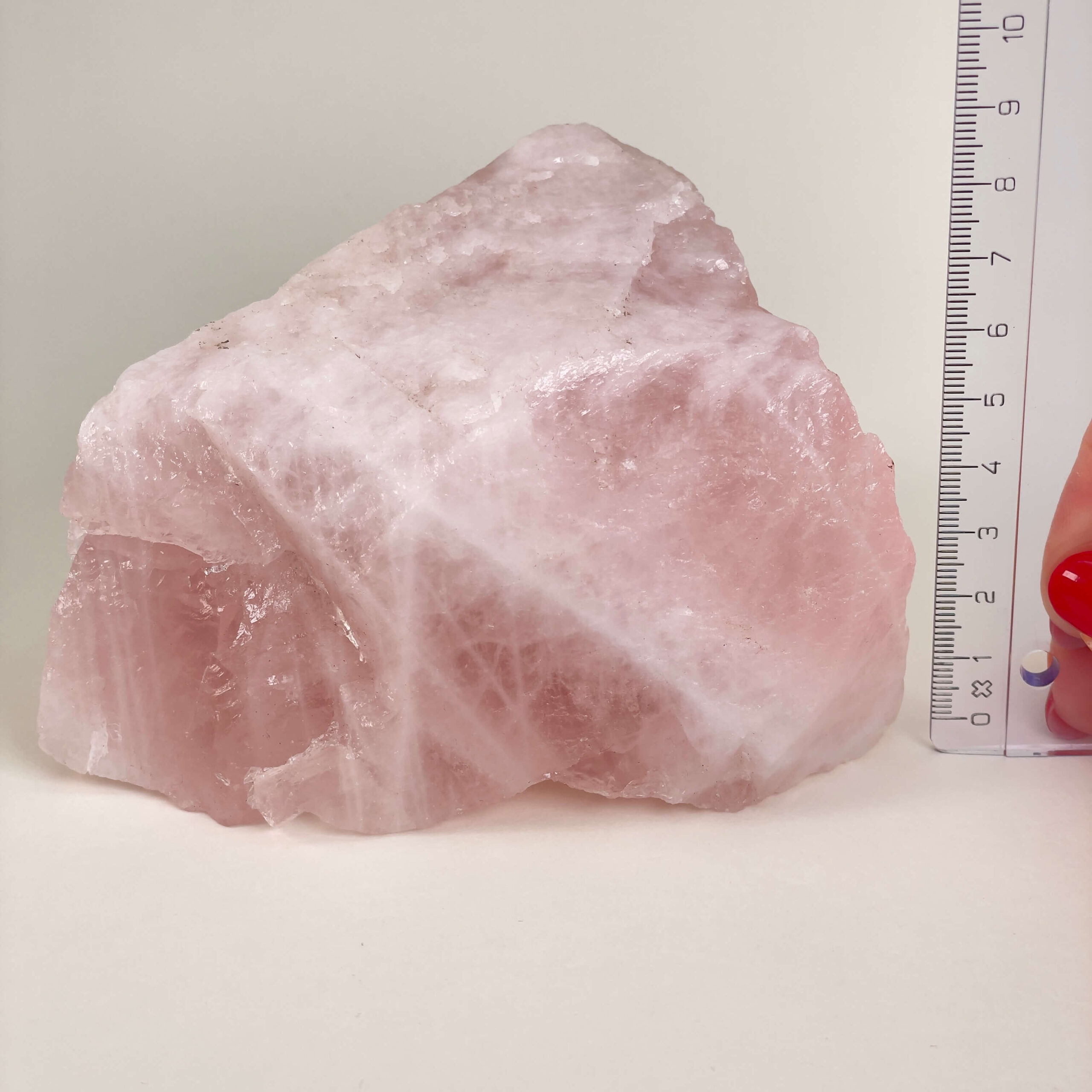 Rosakvarts Rå krystal sten med lineal på hvid baggrund