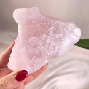 Rosakvarts Rå krystal sten i hånd på hvid baggrund