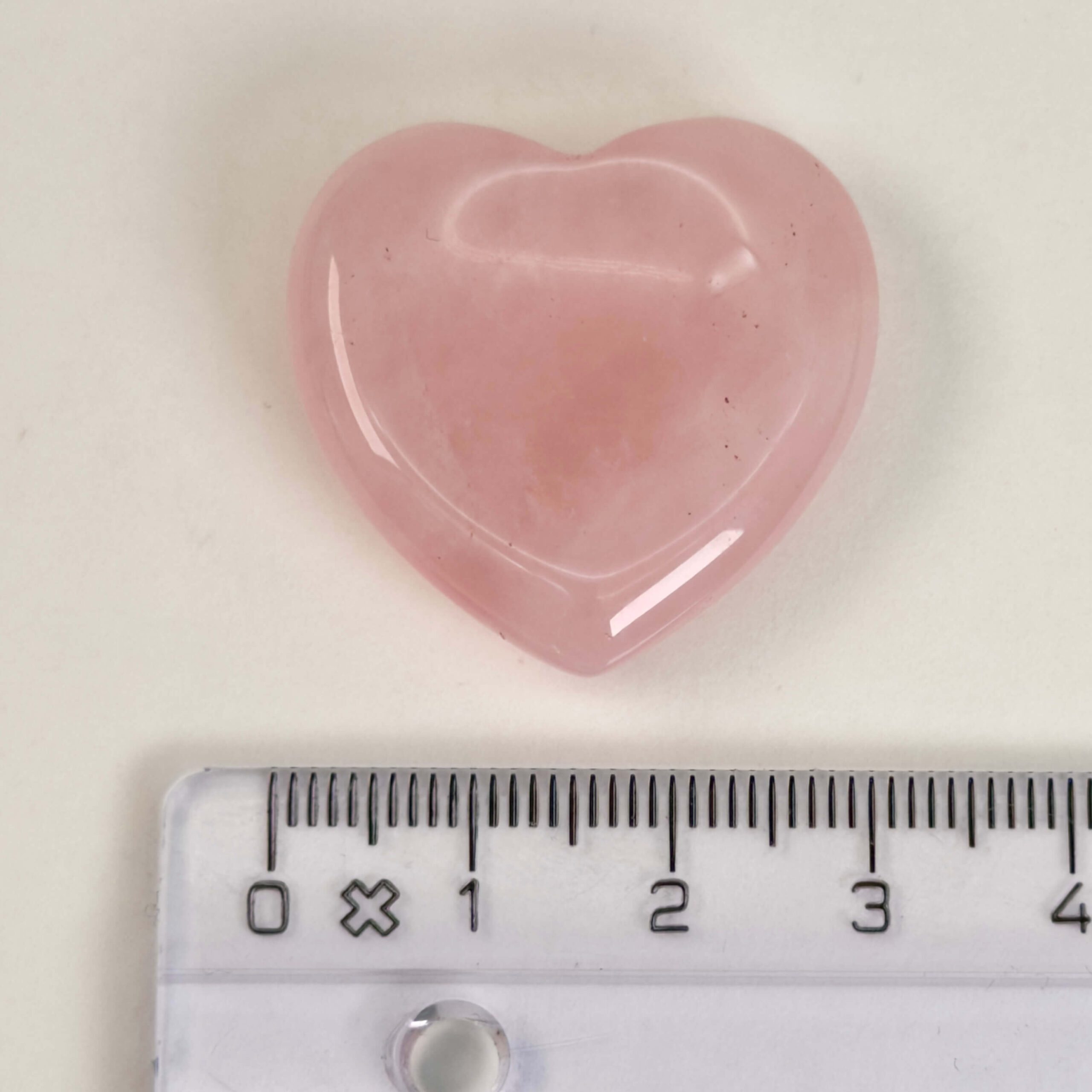 Rosakvarts Hjerte Krystal Sten på hvid baggrund med lineal