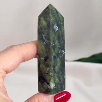 Serpentin Tårn krystal sten i hånd på hvid baggrund