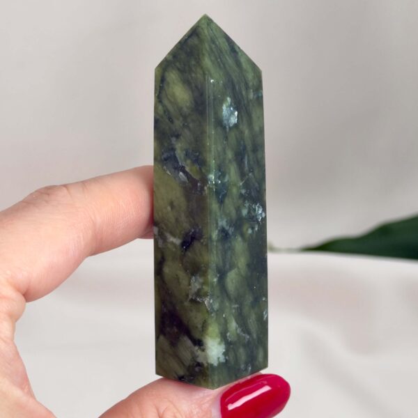 Serpentin Tårn krystal sten i hånd på hvid baggrund