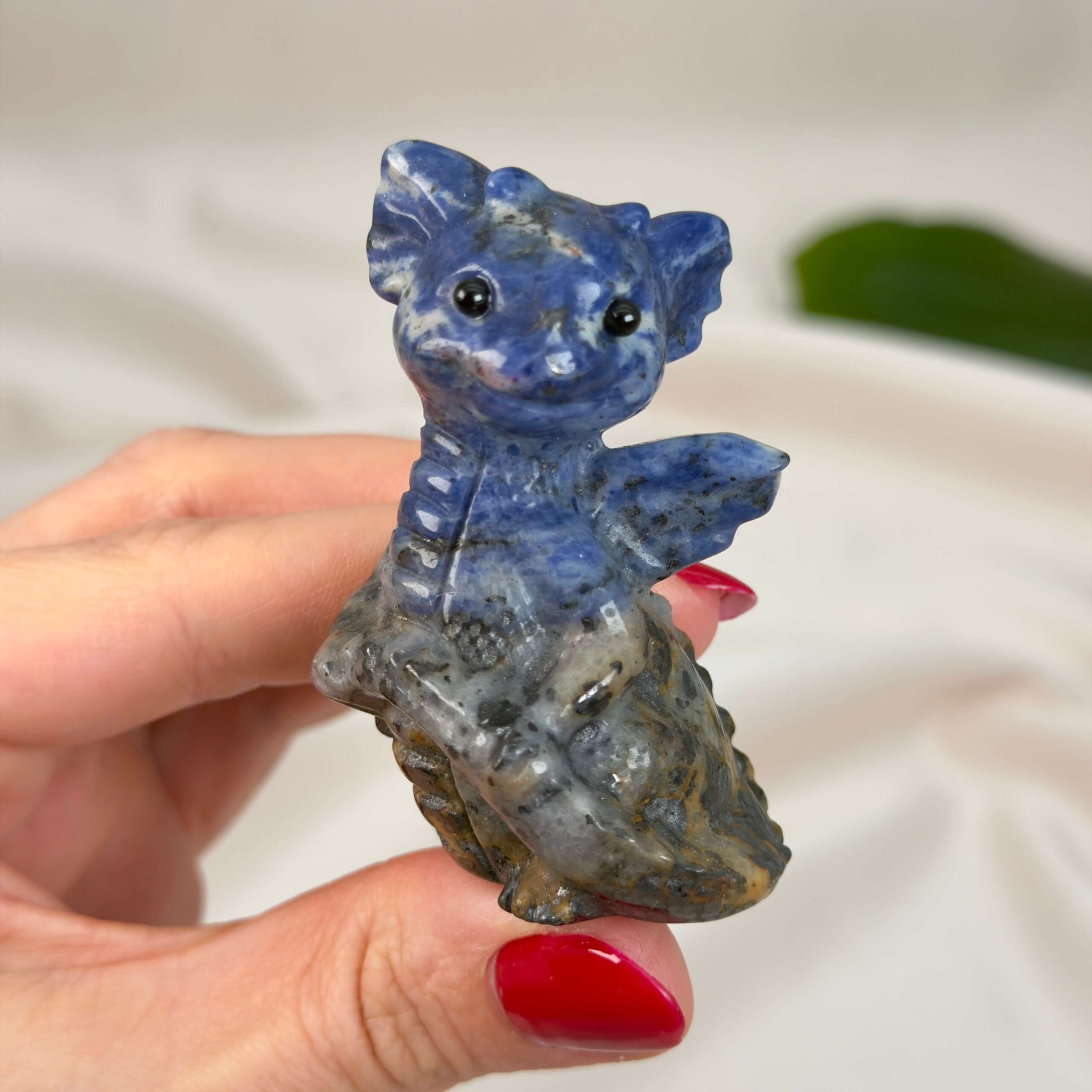 Sodalit Babydrage Krystal sten i hånd på hvid baggrund