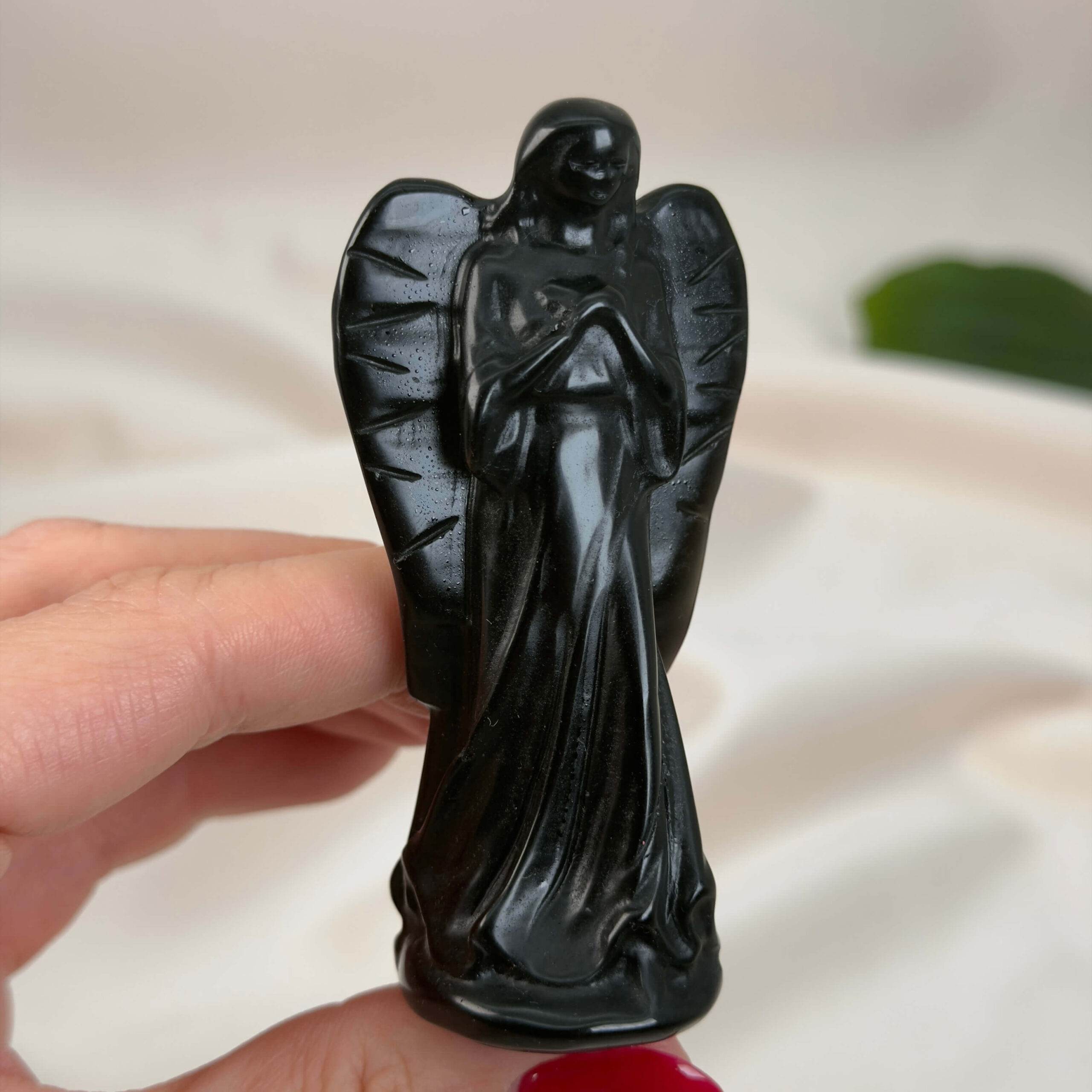 Sort Obsidian Engel krystal sten i hånd på hvid baggrund