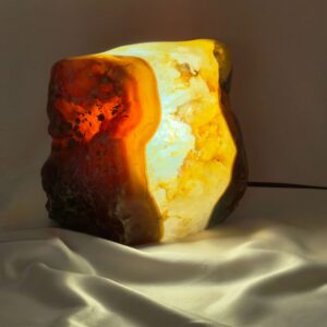 Agat lampe med naturlige bånd og farvespil, der udsender et varmt og roligt lys i rummet.