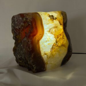 Agat lampe med naturlige bånd og farvespil, der udsender et varmt og roligt lys i rummet.