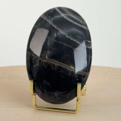 Sort Båndet Onyx Håndsten med glat, poleret overflade og naturlige sorte, grå og hvide bånd, der symboliserer grounding, beskyttelse og indre styrke.