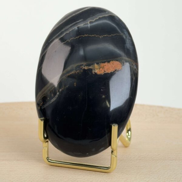 Sort Båndet Onyx Håndsten med glat, poleret overflade og naturlige sorte, grå og hvide bånd, der symboliserer grounding, beskyttelse og indre styrke.