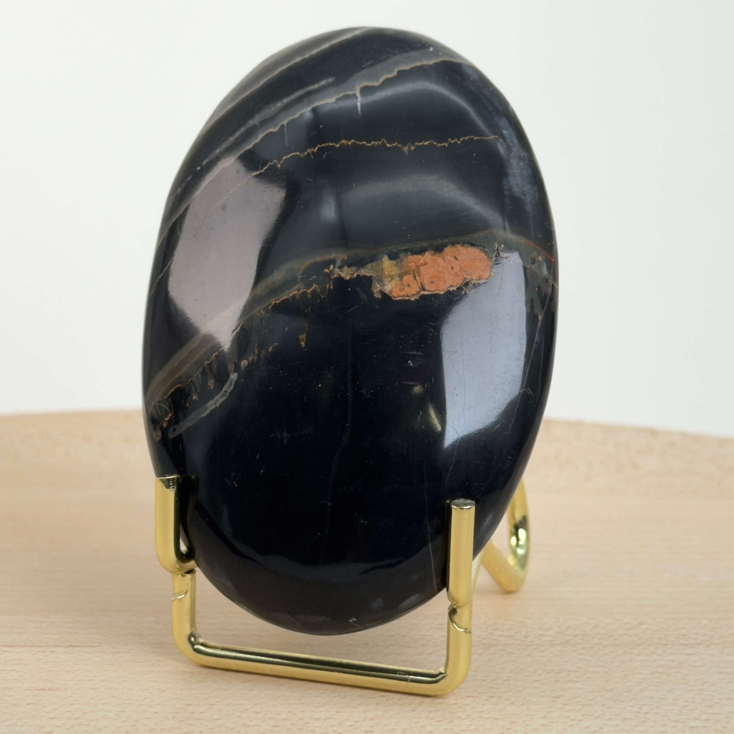 Sort Båndet Onyx Håndsten med glat, poleret overflade og naturlige sorte, grå og hvide bånd, der symboliserer grounding, beskyttelse og indre styrke.