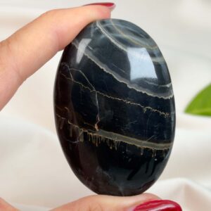 Sort Båndet Onyx Håndsten med glat, poleret overflade og naturlige sorte, grå og hvide bånd, der symboliserer grounding, beskyttelse og indre styrke.