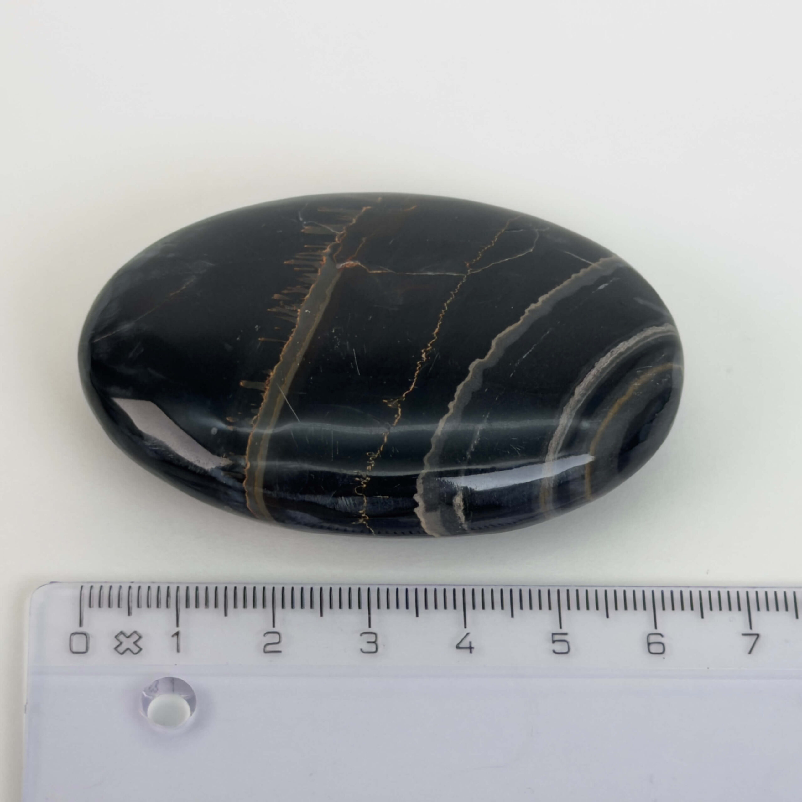 Sort Båndet Onyx Håndsten med glat, poleret overflade og naturlige sorte, grå og hvide bånd, der symboliserer grounding, beskyttelse og indre styrke.