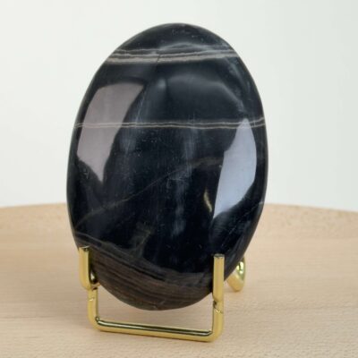 Sort Båndet Onyx Håndsten med glat, poleret overflade og naturlige sorte, grå og hvide bånd, der symboliserer grounding, beskyttelse og indre styrke.