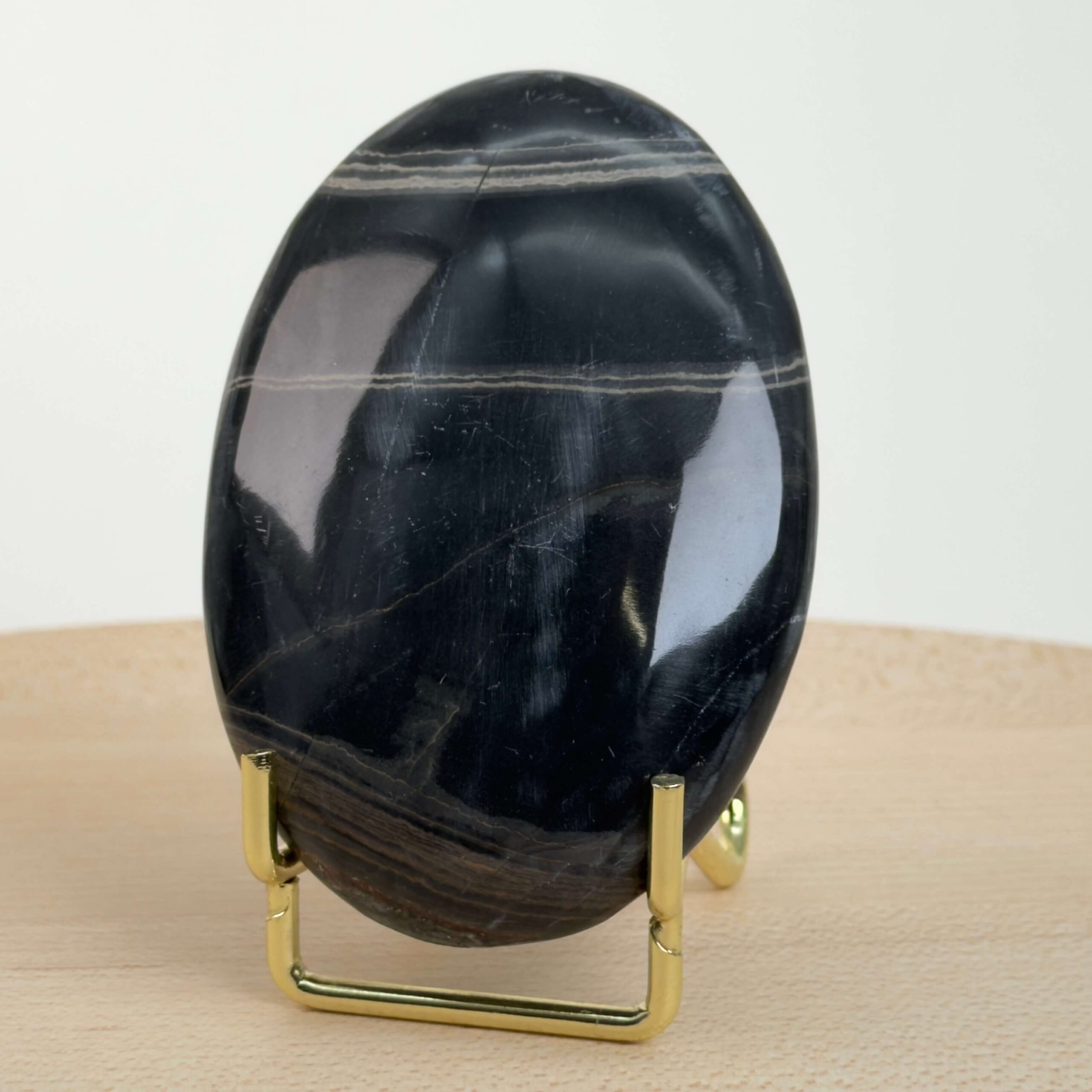 Sort Båndet Onyx Håndsten med glat, poleret overflade og naturlige sorte, grå og hvide bånd, der symboliserer grounding, beskyttelse og indre styrke.