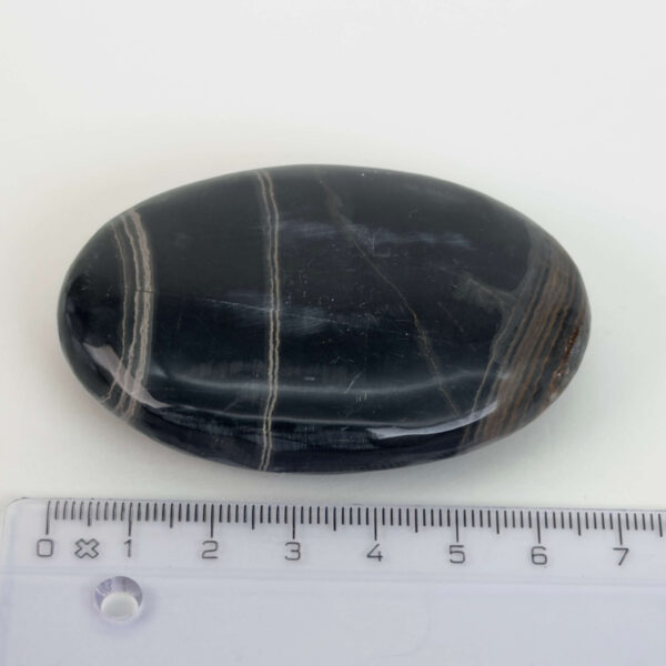 Sort Båndet Onyx Håndsten med glat, poleret overflade og naturlige sorte, grå og hvide bånd, der symboliserer grounding, beskyttelse og indre styrke.
