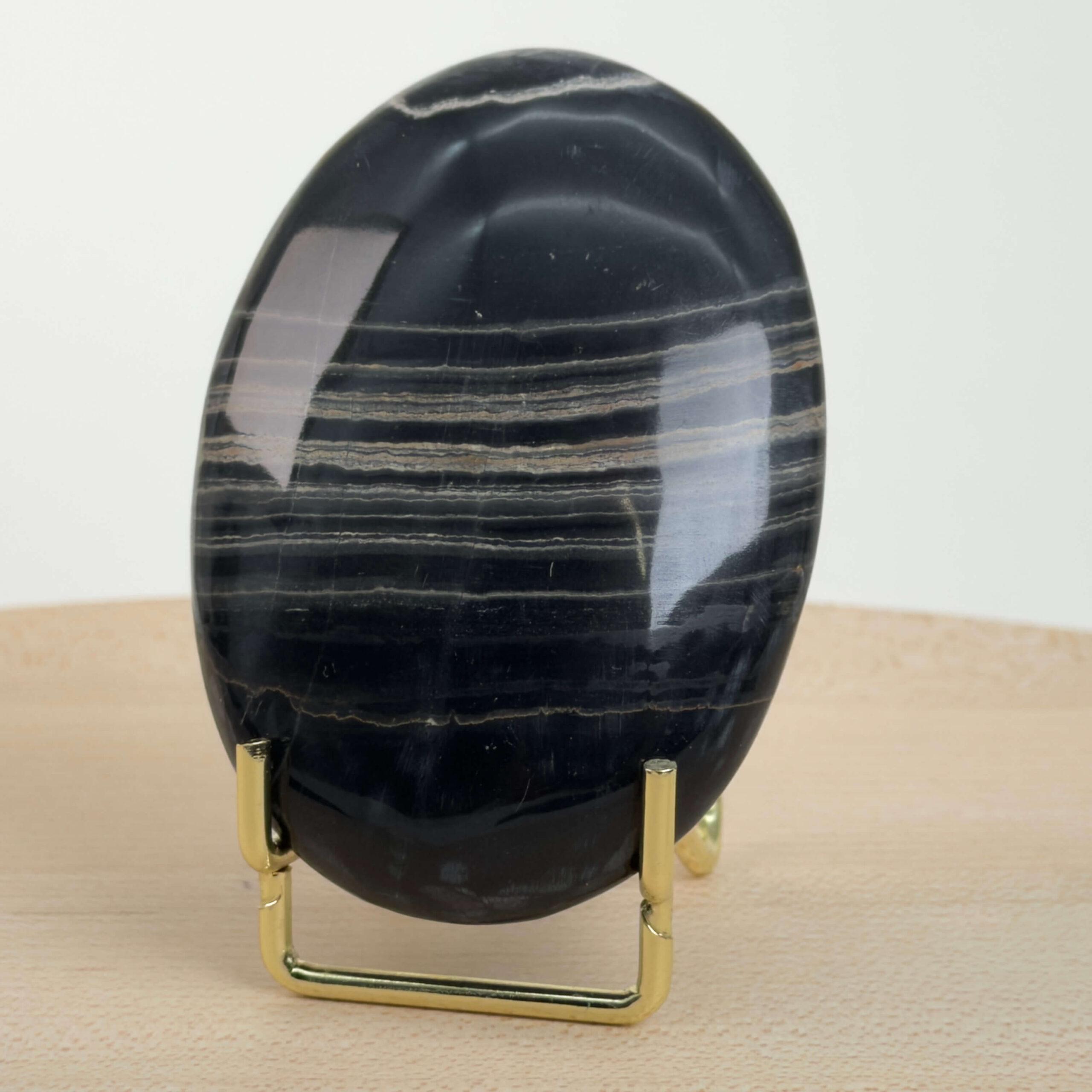 Sort Båndet Onyx Håndsten med glat, poleret overflade og naturlige sorte, grå og hvide bånd, der symboliserer grounding, beskyttelse og indre styrke.