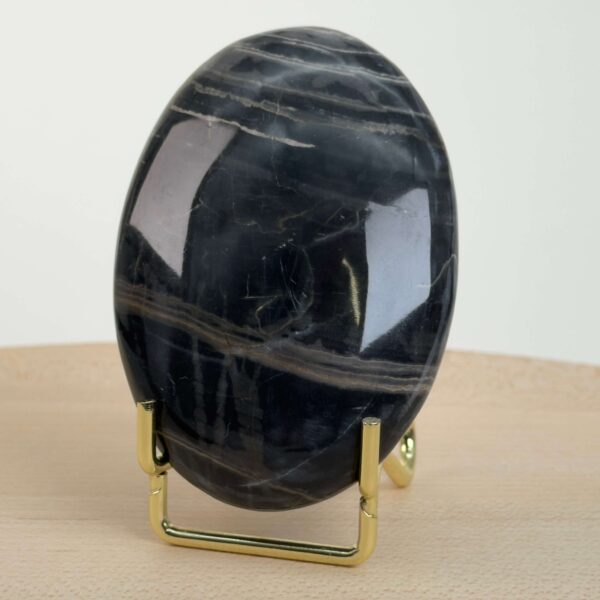 Sort Båndet Onyx Håndsten med glat, poleret overflade og naturlige sorte, grå og hvide bånd, der symboliserer grounding, beskyttelse og indre styrke.