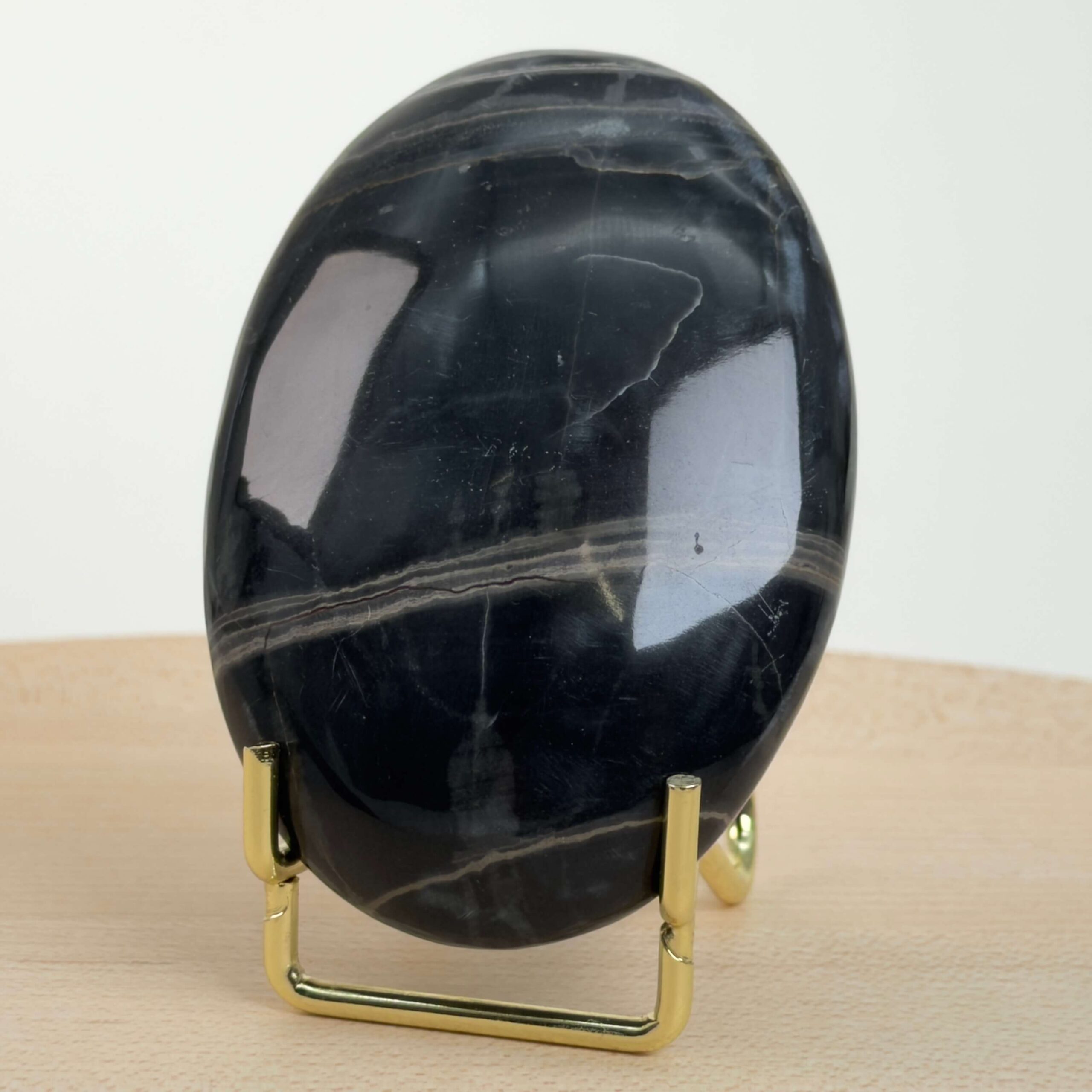Sort Båndet Onyx Håndsten med glat, poleret overflade og naturlige sorte, grå og hvide bånd, der symboliserer grounding, beskyttelse og indre styrke.