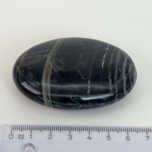 Sort Båndet Onyx Håndsten med glat, poleret overflade og naturlige sorte, grå og hvide bånd, der symboliserer grounding, beskyttelse og indre styrke.