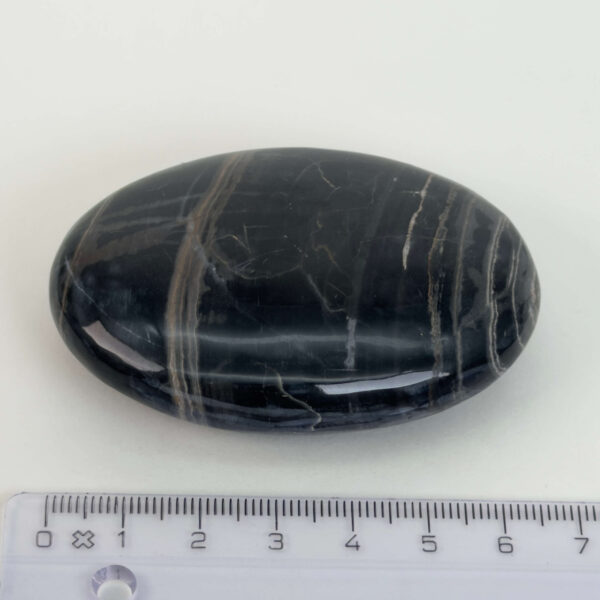 Sort Båndet Onyx Håndsten med glat, poleret overflade og naturlige sorte, grå og hvide bånd, der symboliserer grounding, beskyttelse og indre styrke.