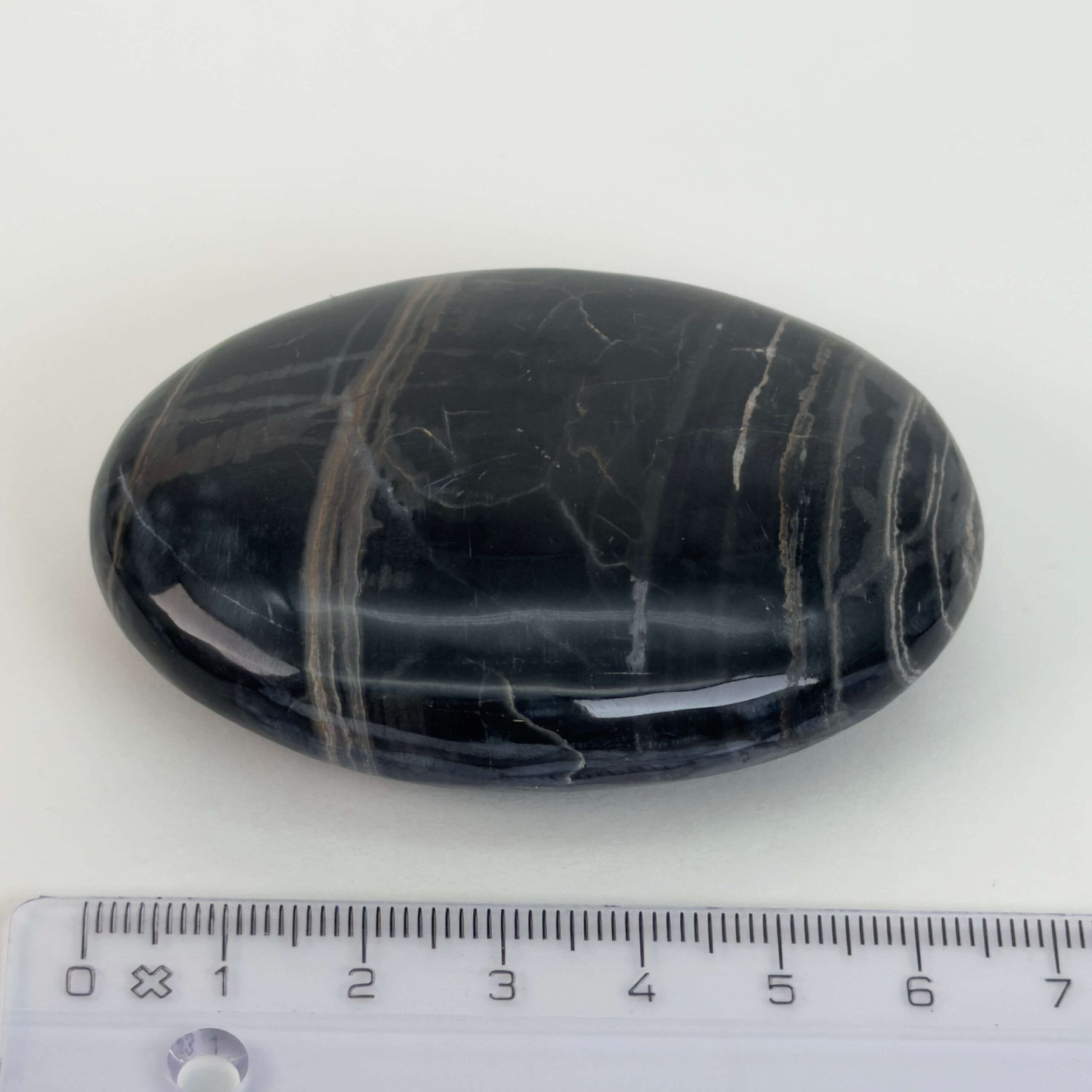 Sort Båndet Onyx Håndsten med glat, poleret overflade og naturlige sorte, grå og hvide bånd, der symboliserer grounding, beskyttelse og indre styrke.