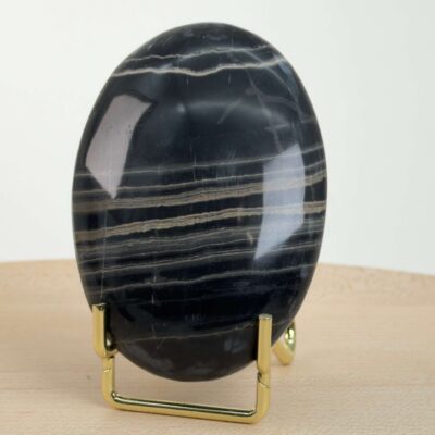 Sort Båndet Onyx Håndsten med glat, poleret overflade og naturlige sorte, grå og hvide bånd, der symboliserer grounding, beskyttelse og indre styrke.