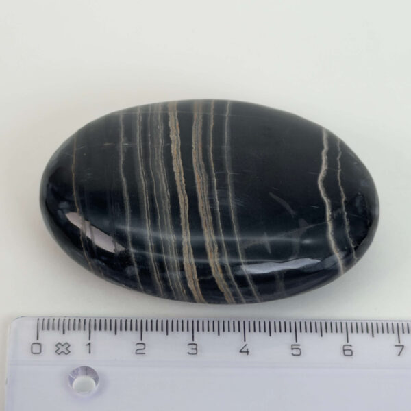 Sort Båndet Onyx Håndsten med glat, poleret overflade og naturlige sorte, grå og hvide bånd, der symboliserer grounding, beskyttelse og indre styrke.