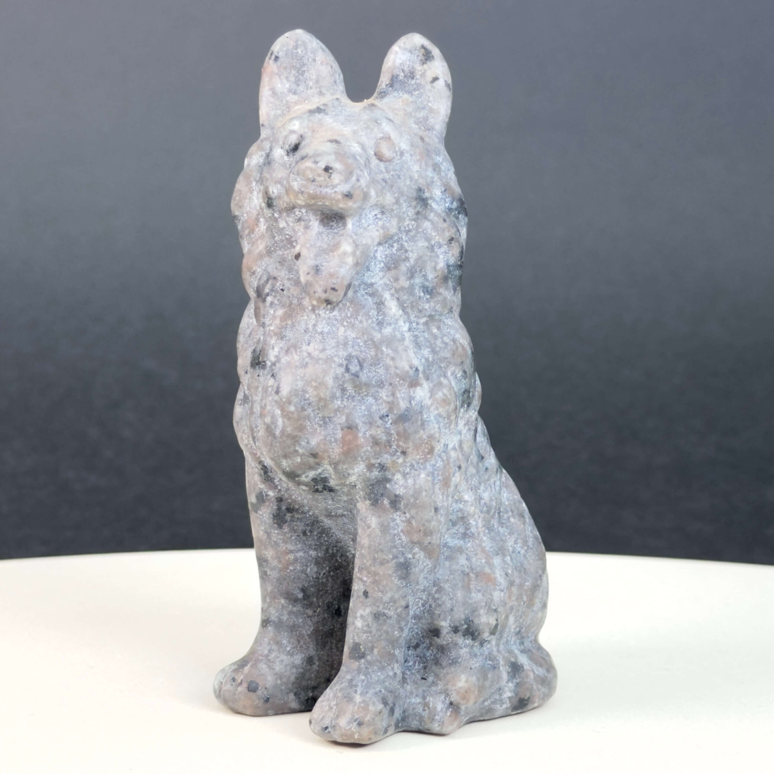 Yooperlite Ulvehund med naturlige grå nuancer og orange fluorescens under UV-lys samt symbolik for loyalitet, intuition og indre styrke.