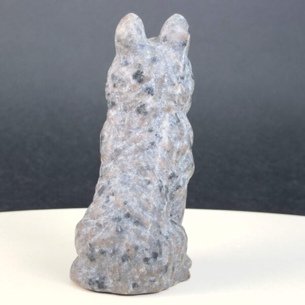 Yooperlite Ulvehund med naturlige grå nuancer og orange fluorescens under UV-lys samt symbolik for loyalitet, intuition og indre styrke.