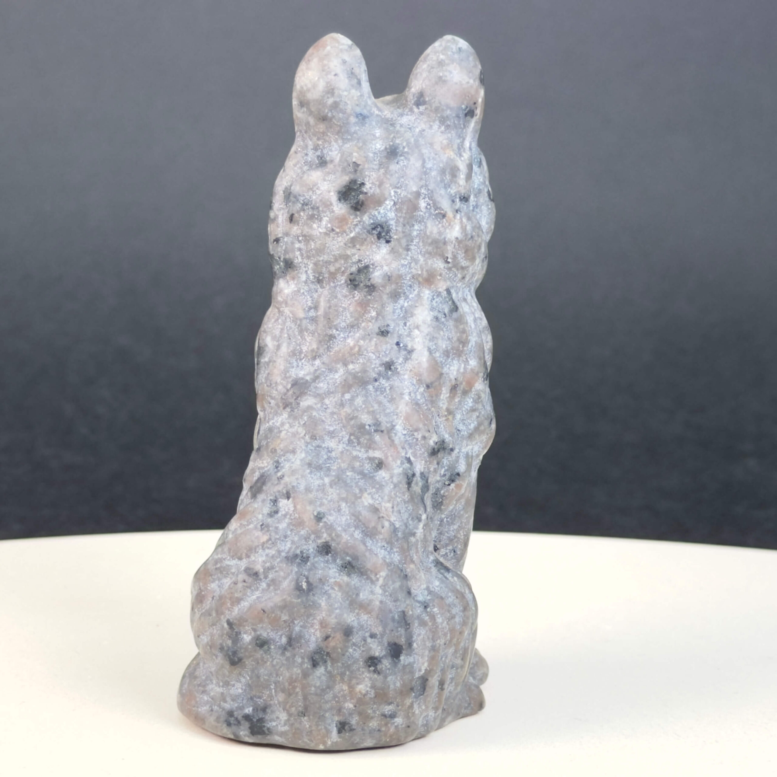 Yooperlite Ulvehund med naturlige grå nuancer og orange fluorescens under UV-lys samt symbolik for loyalitet, intuition og indre styrke.