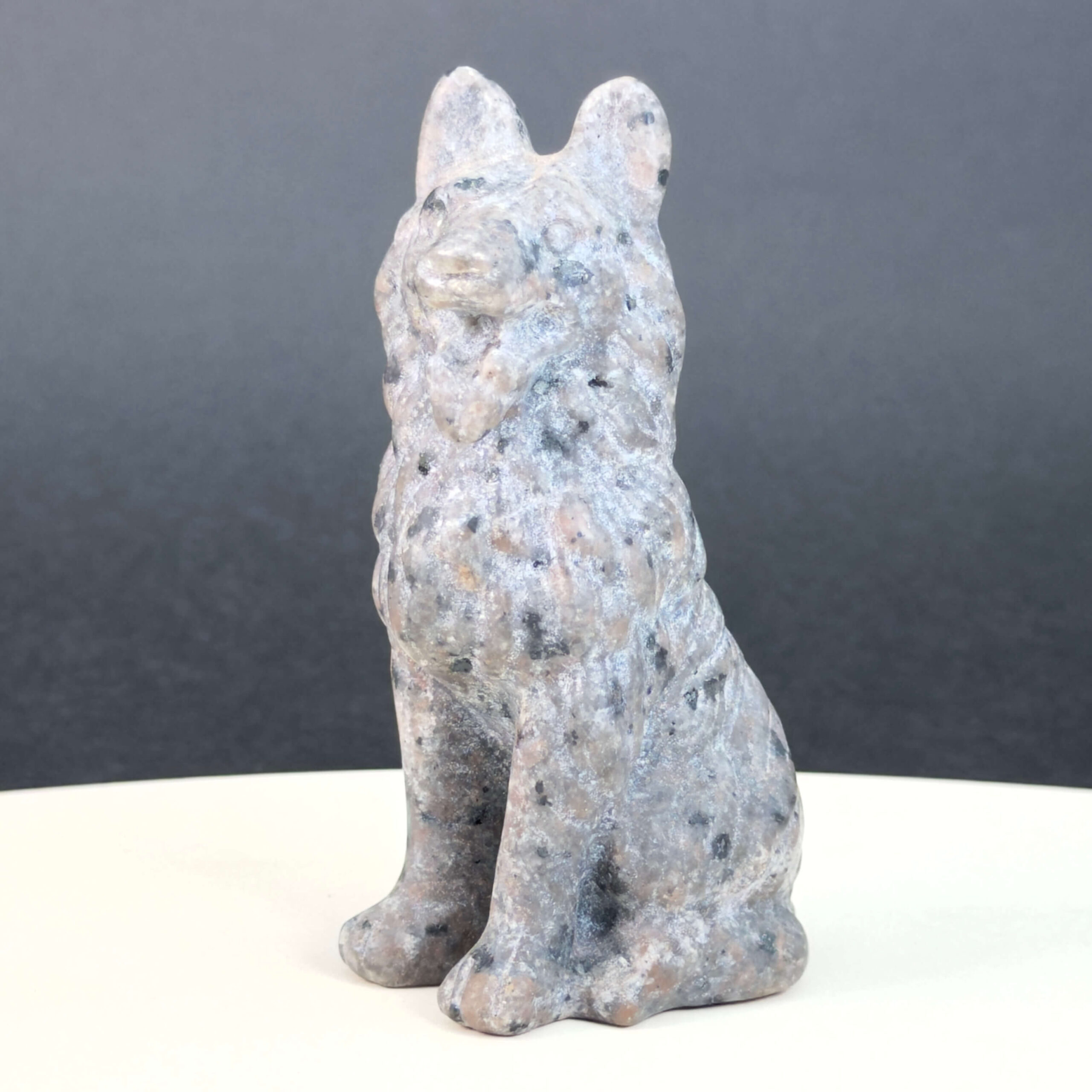 Yooperlite Ulvehund med naturlige grå nuancer og orange fluorescens under UV-lys samt symbolik for loyalitet, intuition og indre styrke.