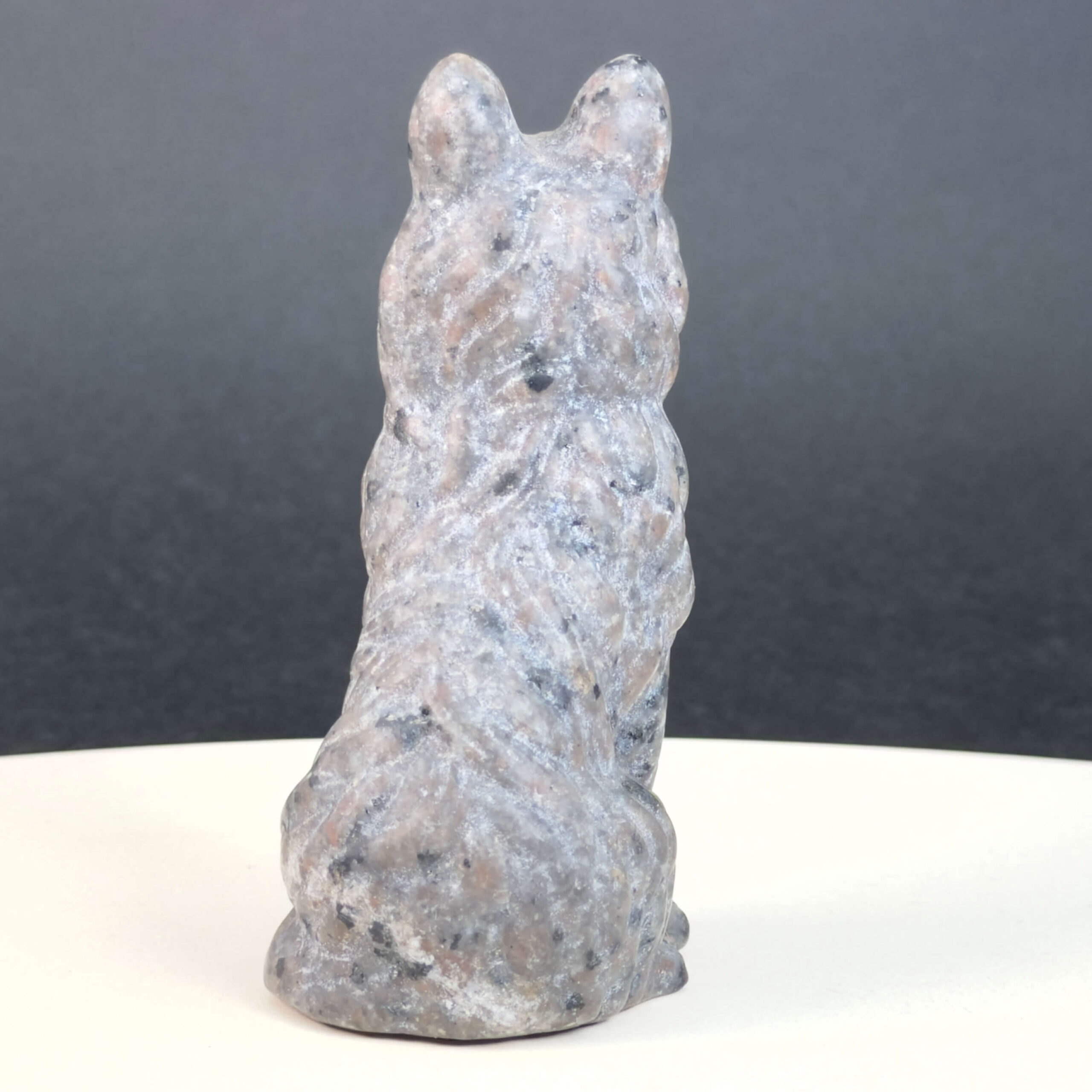 Yooperlite Ulvehund med naturlige grå nuancer og orange fluorescens under UV-lys samt symbolik for loyalitet, intuition og indre styrke.