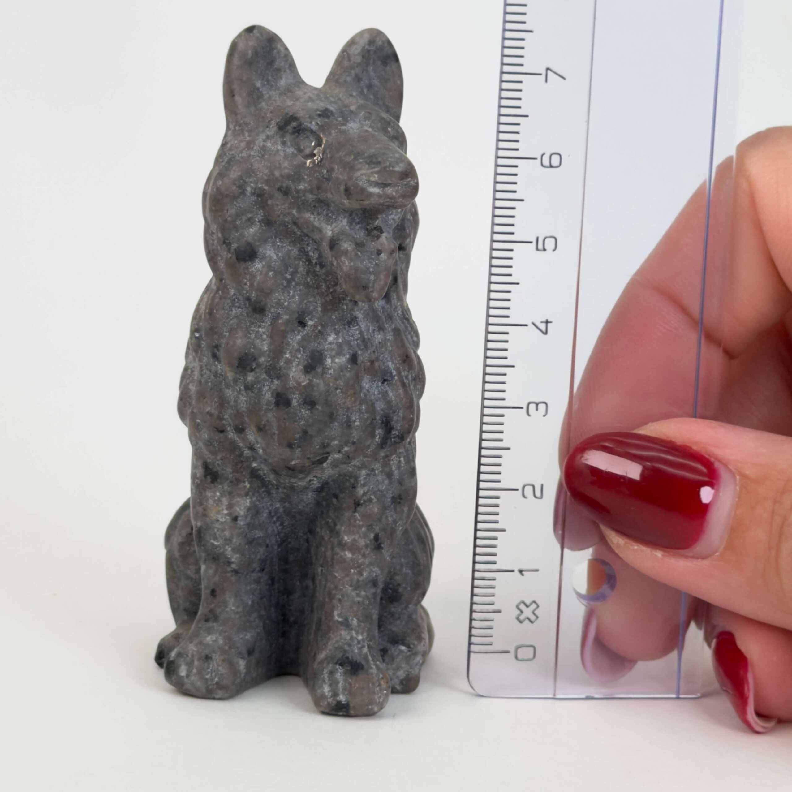 Yooperlite Ulvehund med naturlige grå nuancer og orange fluorescens under UV-lys samt symbolik for loyalitet, intuition og indre styrke.