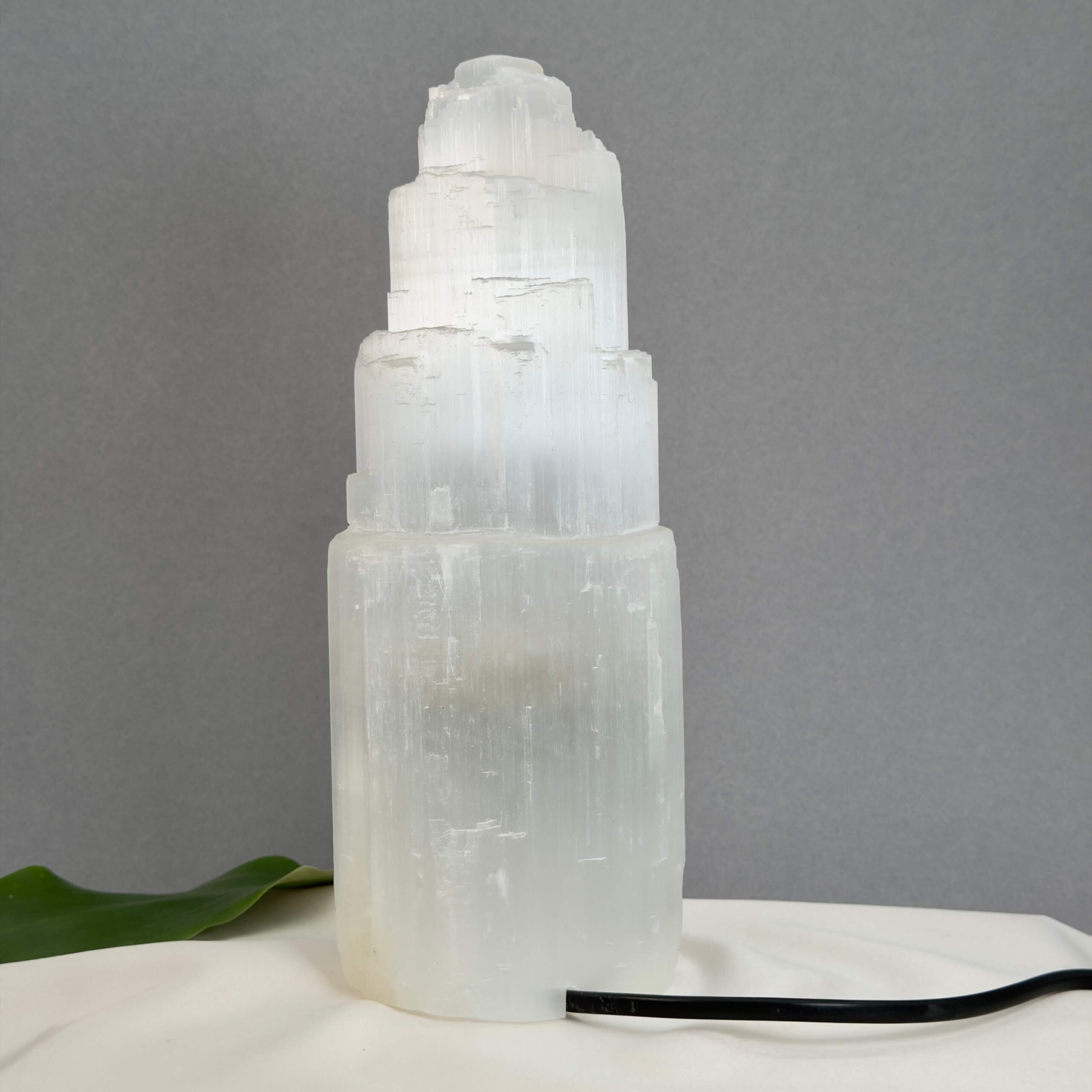 Unik Selenit lampe formet som tårn med naturlige lyse lag og struktur